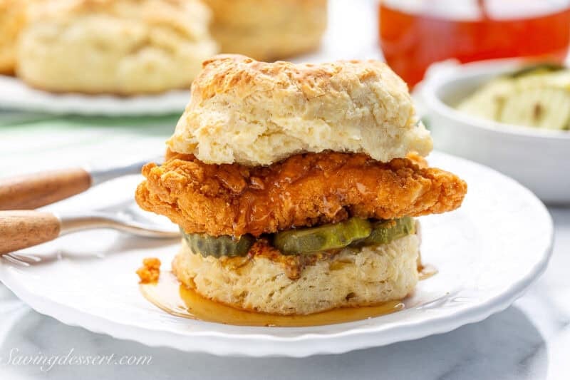 A side view of a big fried chicken biscuit on a plate.