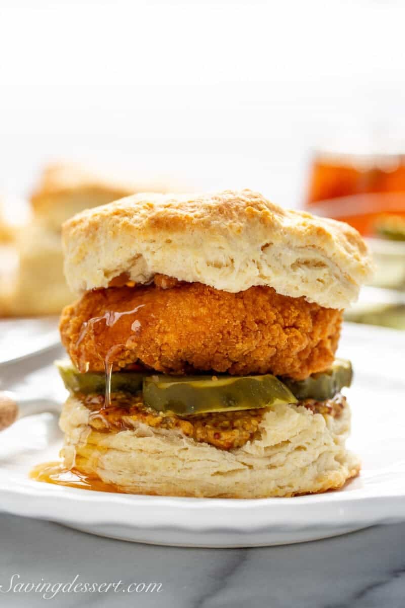 Chicken biscuit on a plate with honey dripping down the side.