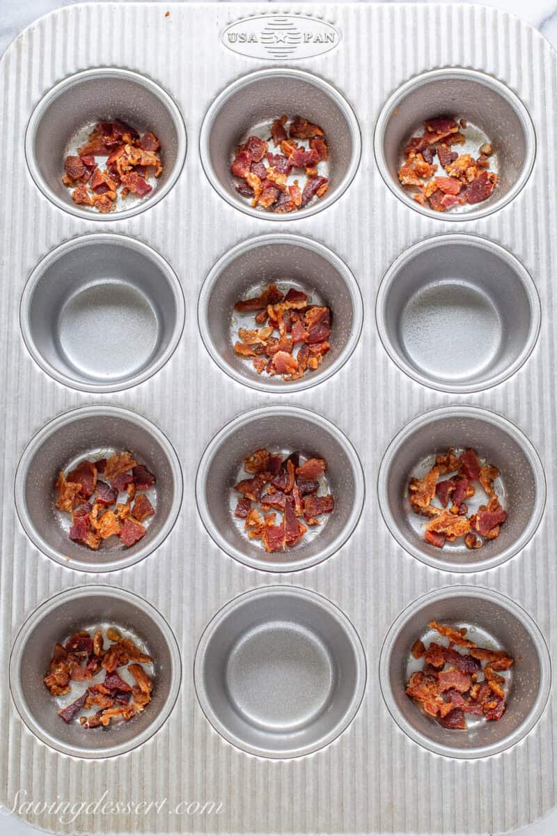 Bacon crumbled in the bottom of nine muffin tin wells.