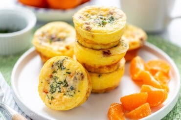 A stack of egg muffins on a plate with clementine sections.