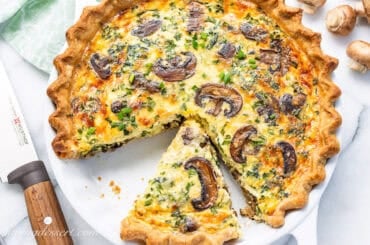 An overhead shot of a sliced spinach and mushroom quiche.