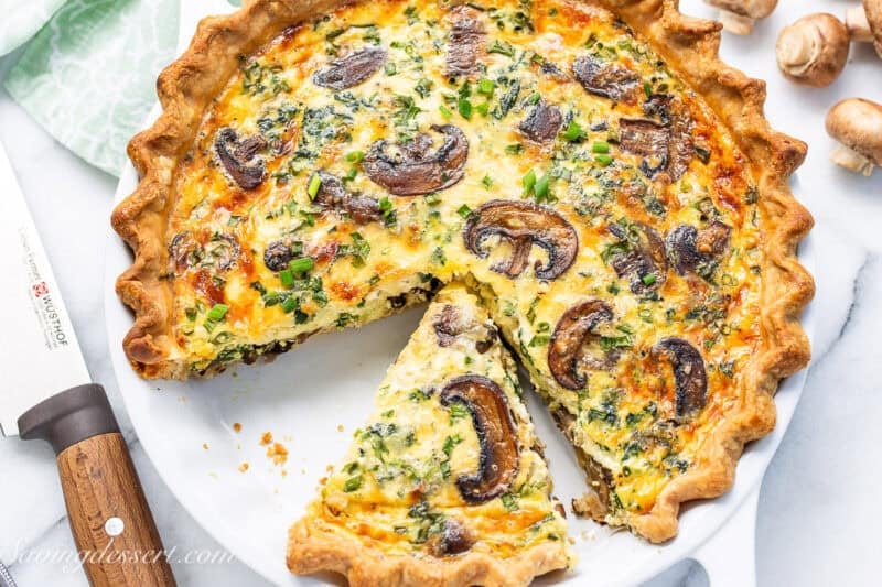 An overhead shot of a sliced spinach and mushroom quiche.
