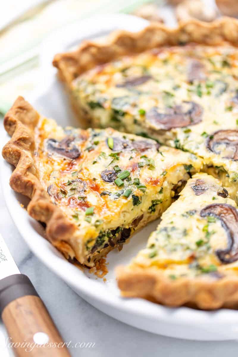 A sliced spinach and mushroom quiche in a pie pan.
