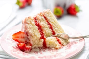 A fork cutting into a slice of strawberry cake.