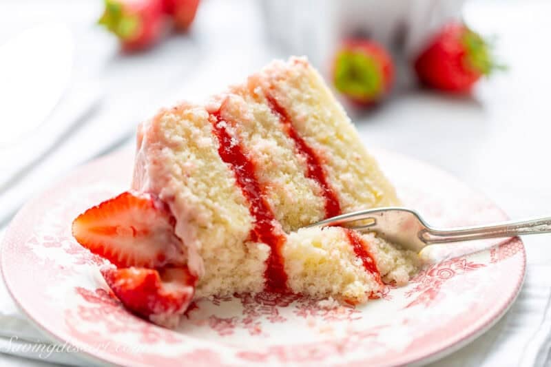 A fork cutting into a slice of strawberry cake.