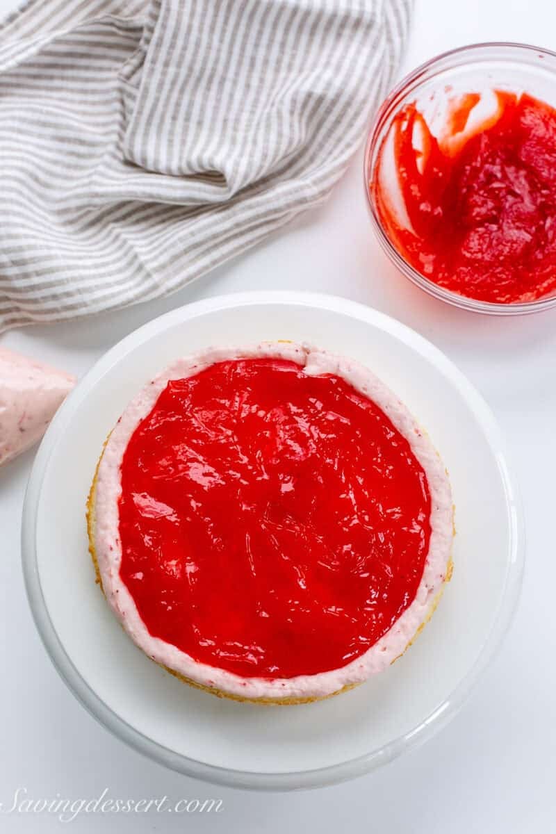A cake layer with a ring of frosting around the outside to hold a strawberry jam spread in the center.