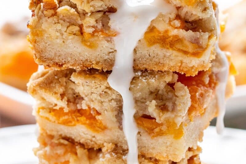 A stack of apricot bars with an icing dripping down the sides.