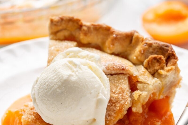 A slice of fresh apricot pie with ice cream on top.
