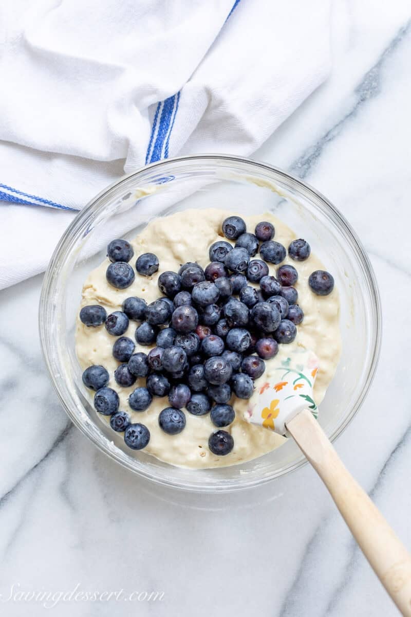 Blueberries being folded into a bowl of pancake batter.