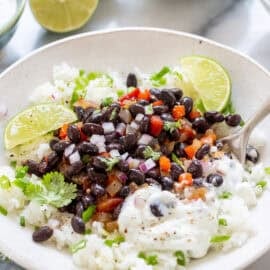A bowl of rice with black beans, peppers, onions and tomatoes.