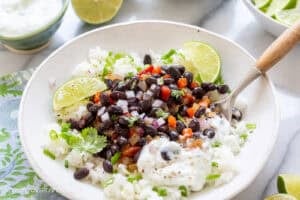 A bowl of rice with black beans, peppers, onions and tomatoes.