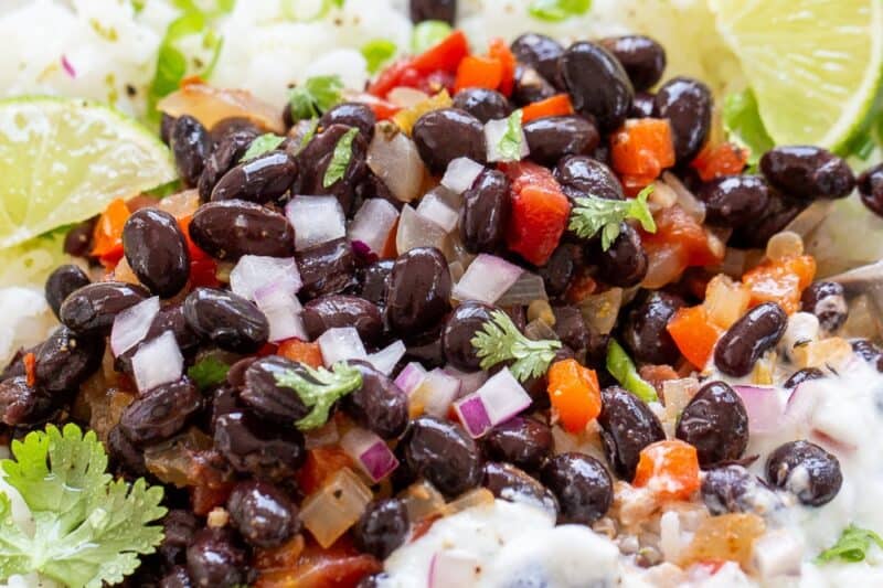 Black beans and rice served in a bowl with lime wedges and a lime crema.