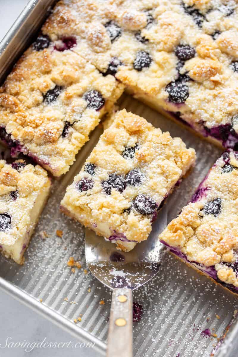 An overhead shot of a pan of blueberry cheesecake bars sliced into squares.