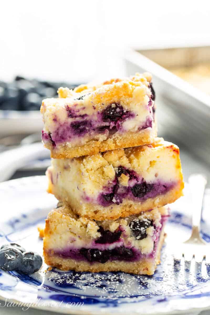 A stack of three blueberry cheesecake crumb bars on a blue plate.