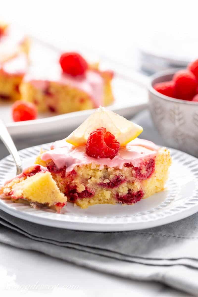 A lemon raspberry bar on a plate with a portion on a small fork.