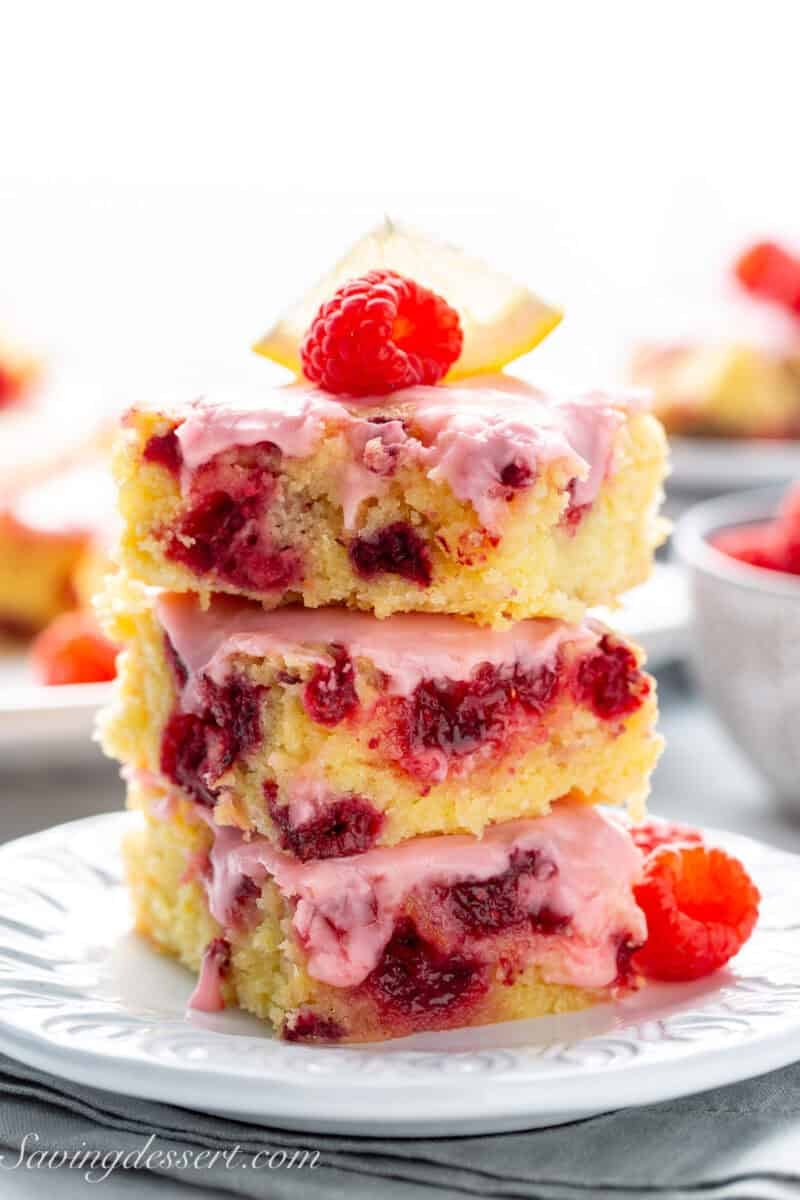 A stack of lemon and raspberry blondies topped with a pink lemon icing.