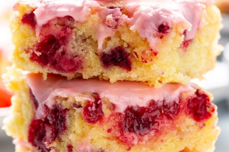A stack of lemon raspberry blondies with a fresh raspberry on top.