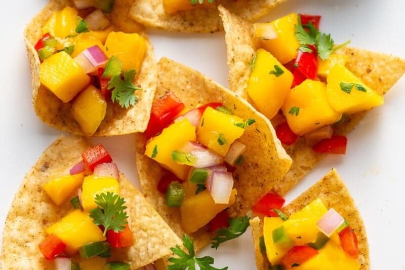 A platter of chips topped with mango salsa.