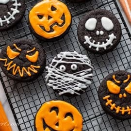 An overhead view of a cooling rack of chocolate cookies decorated for Halloween.