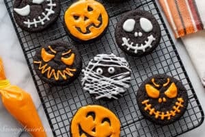 An overhead view of a cooling rack of chocolate cookies decorated for Halloween.