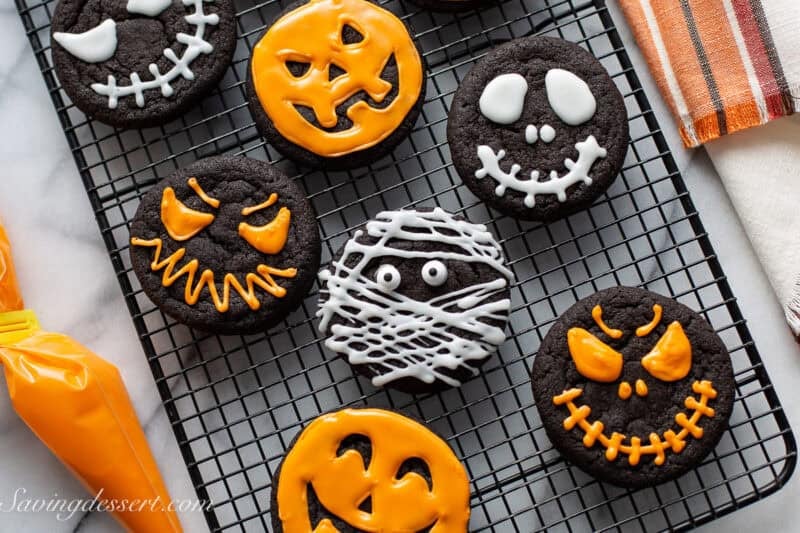 An overhead view of a cooling rack of chocolate cookies decorated for Halloween.