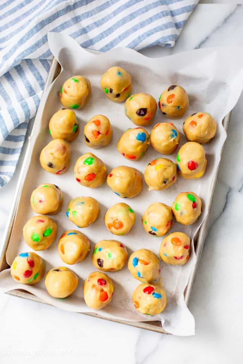 Cookie dough balls with M&Ms on a small baking tray.