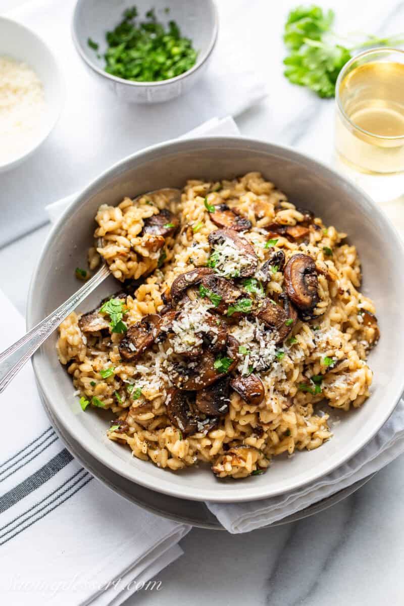 A bowl of mushroom risotto with parsley and Parmesa on top.