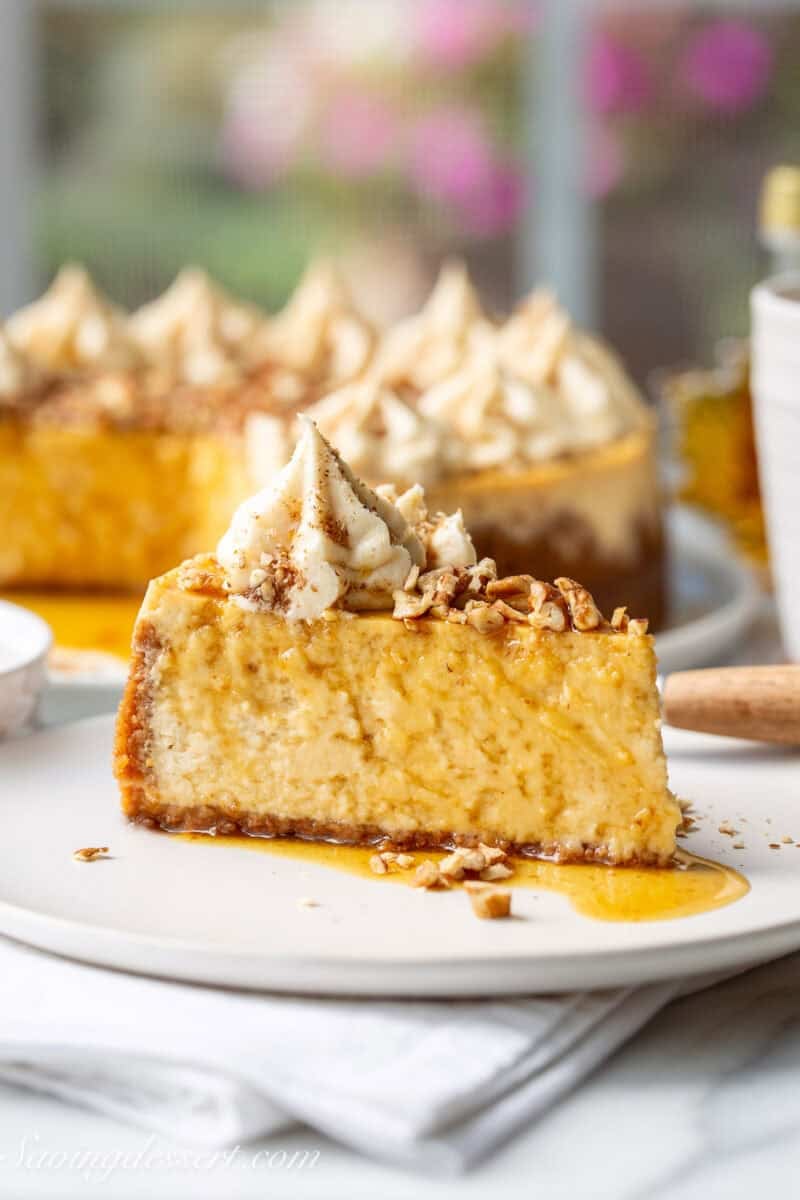 A side view of a slice of maple cheesecake topped with pecans.