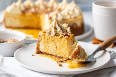 A slice of maple cheesecake on a plate with a fork cutting a corner piece off.