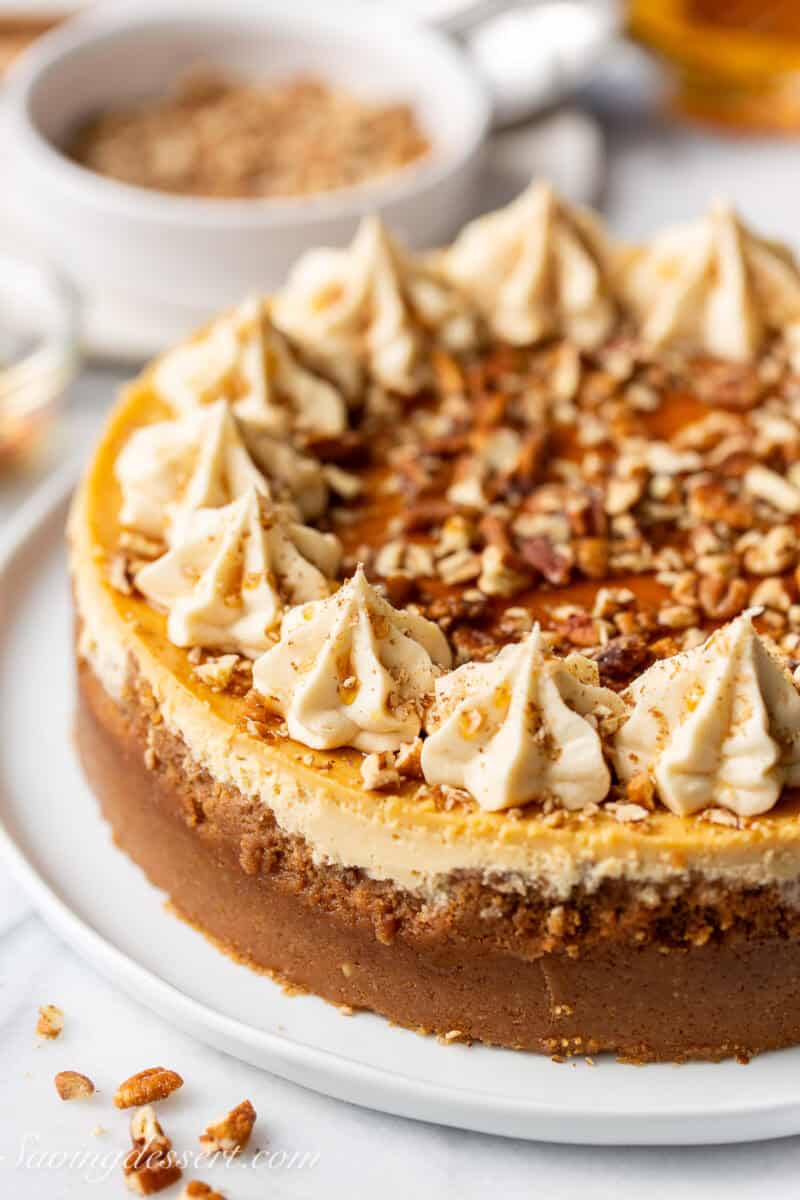 A side view of a maple cheesecake with pecans and maple syrup on top.