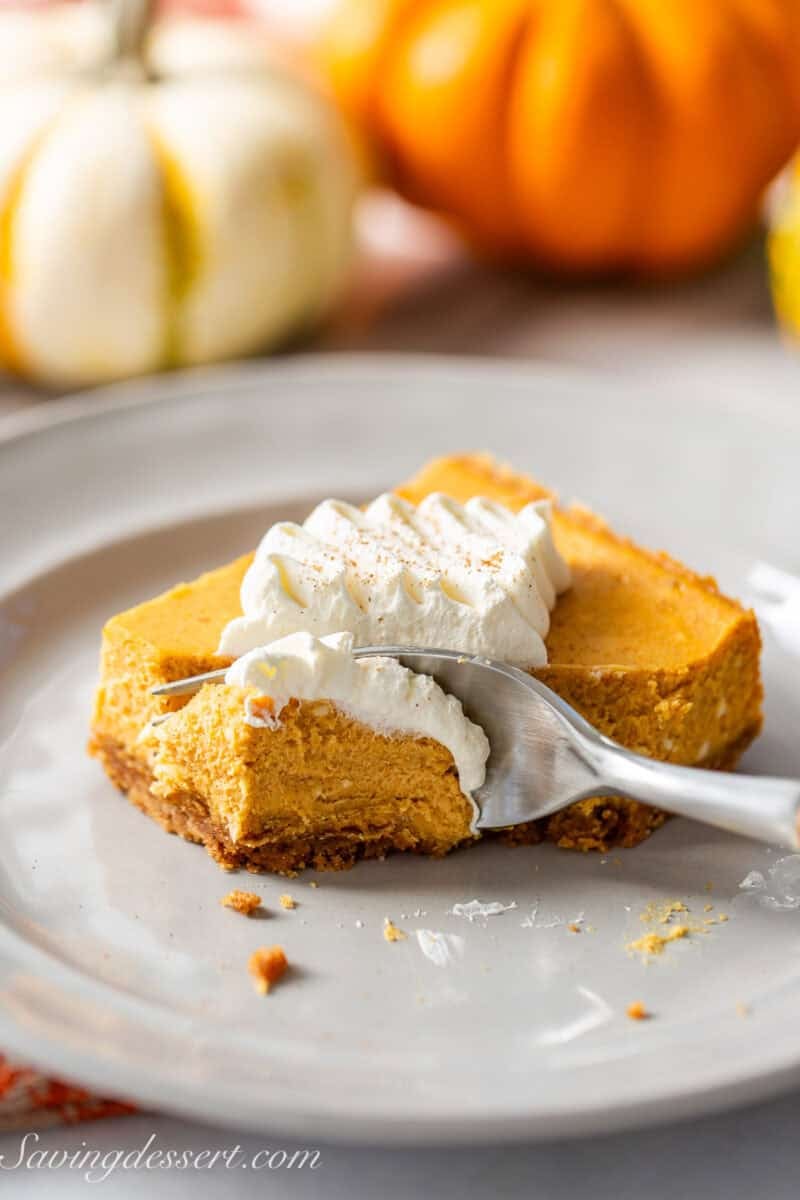 A pumpkin pie square with a fork cutting off the corner piece.