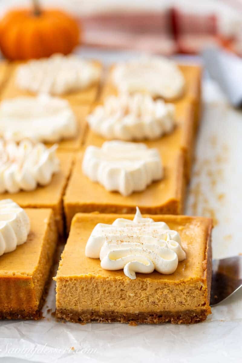 Pumpkin Pie Bars on parchment paper with one being lifted out with a spatula.