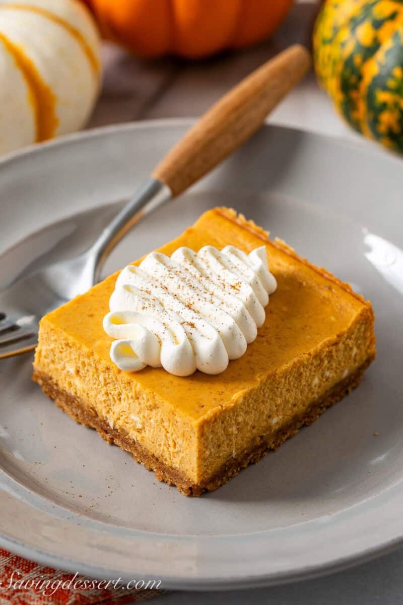 A pumpkin pie square on a plate with a fork on the side.