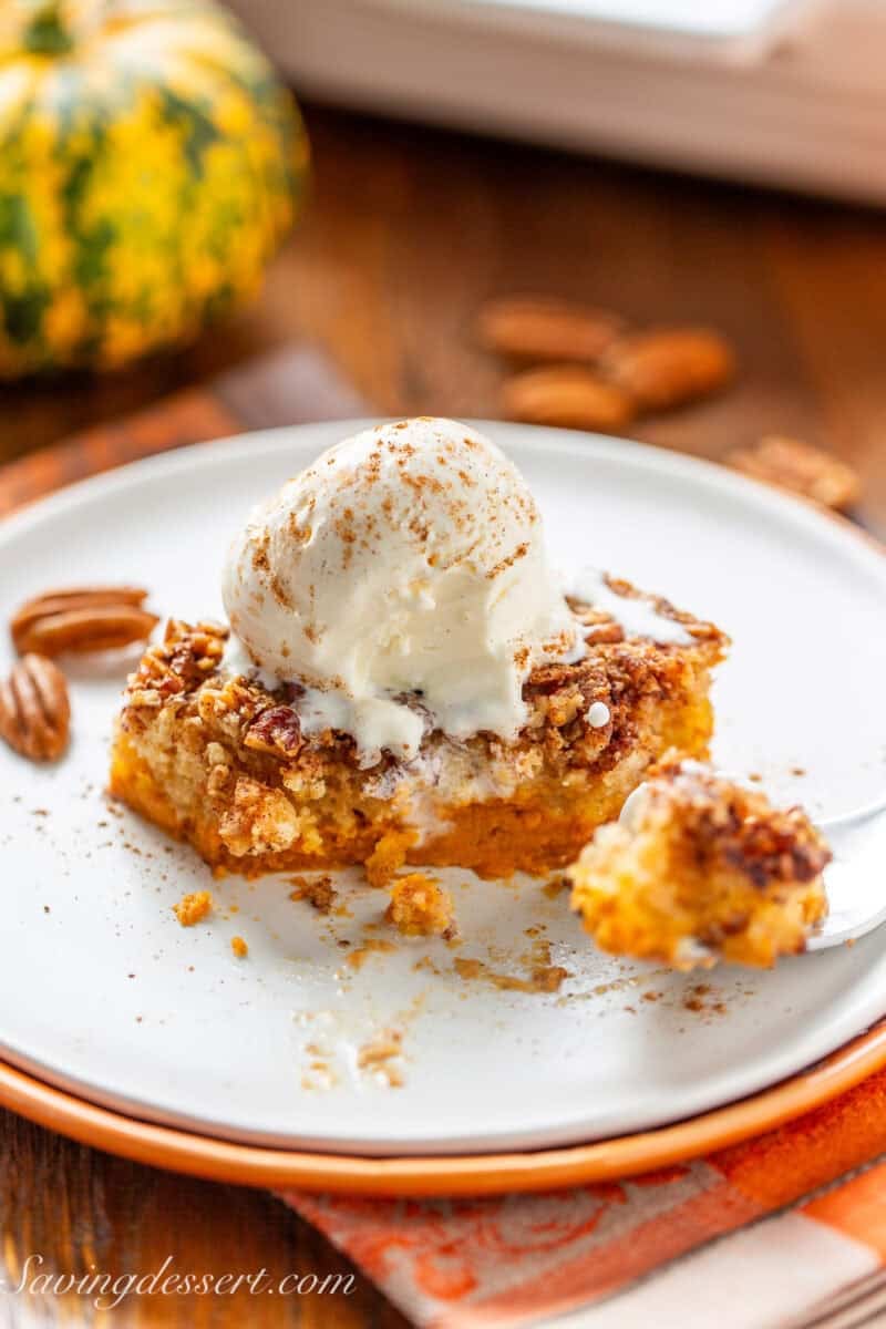 A piece of pumpkin dump cake with a scoop of melting ice cream on top.