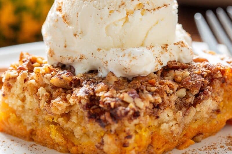 A closeup of a piece of pumpkin dump cake topped with cake mix.