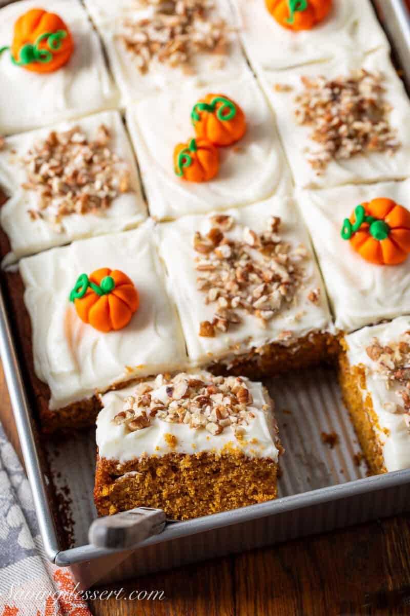 A pan of sliced pumpkin spice cake with a piece being lifted out on the spatula.