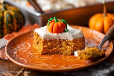 A piece of pumpkin cake on a plate with a fork.