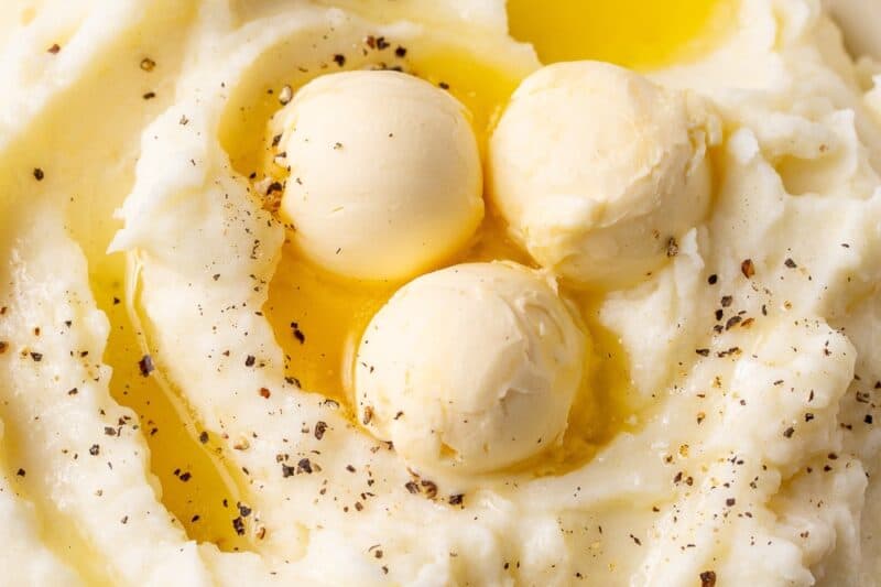 An overhead shot of a bowl of mashed potatoes with melted butter on top.