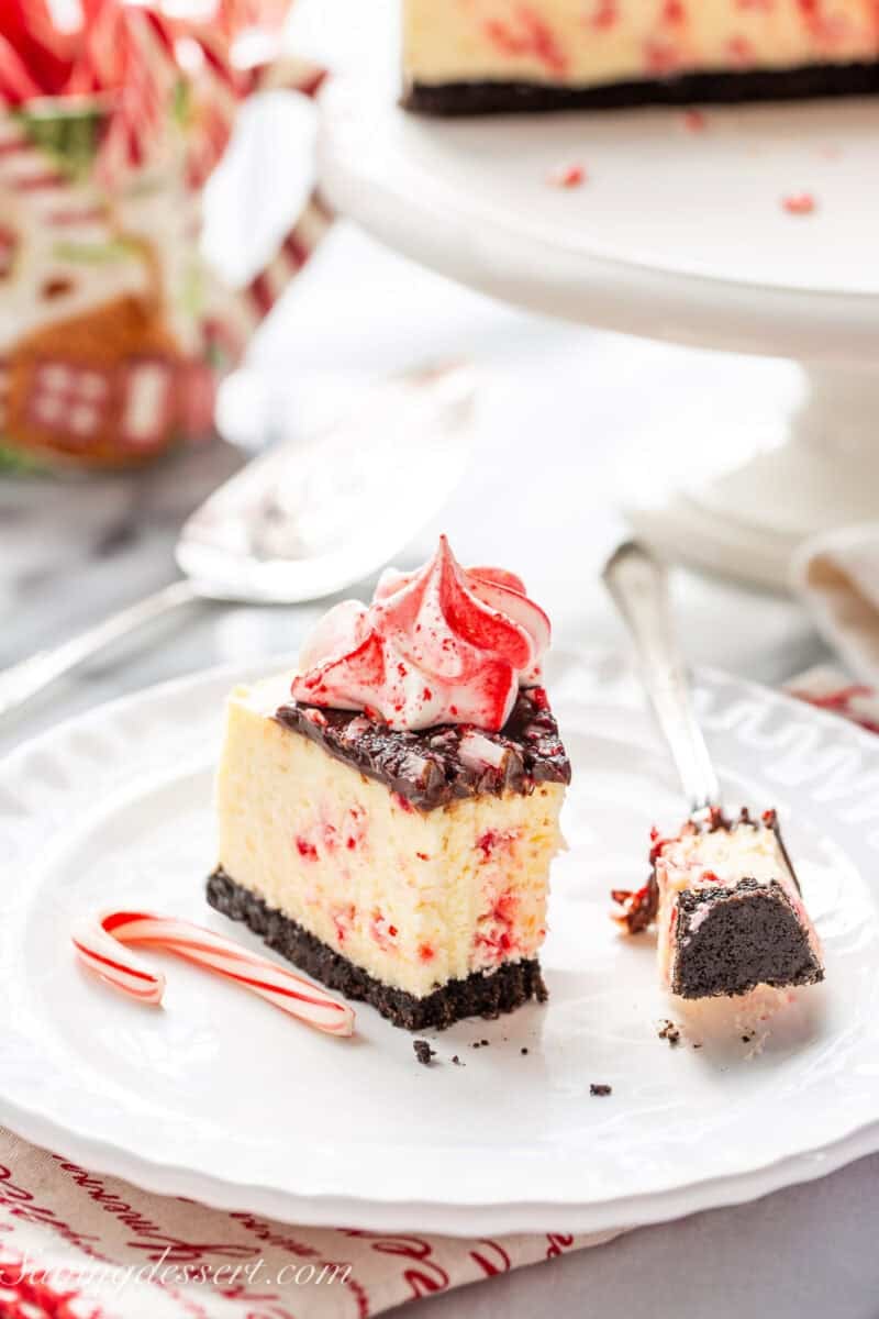 A slice of peppermint cheesecake on a plate with a candy cane on the side.