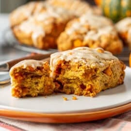 A pumpkin scone on a plate broken ope to show a soft interior.