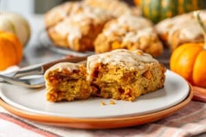 A pumpkin scone on a plate broken ope to show a soft interior.