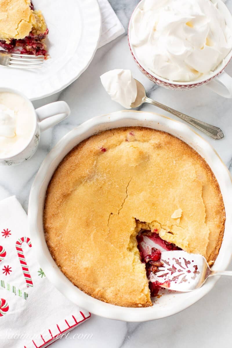 An overhead of a Nantucket Pie with one slice removed being served with whipped cream.