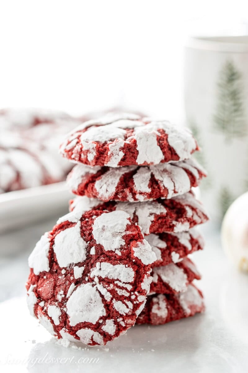 A stack of red velvet crinkle cookies with one propped up on the side.