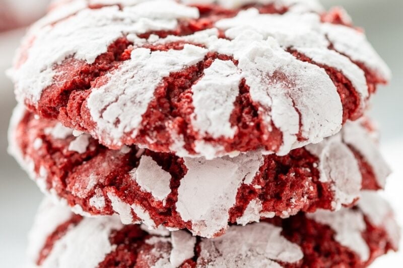 A stack of red velvet crinkle cookies with a powdered sugar coating.