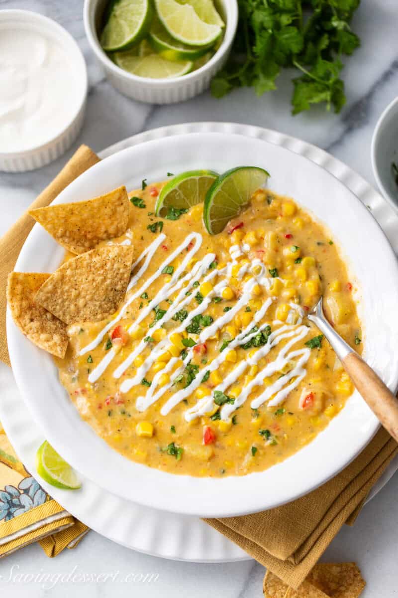 Mexican Street Corn Chowder in a bowl with chips and lime wedges on the side.