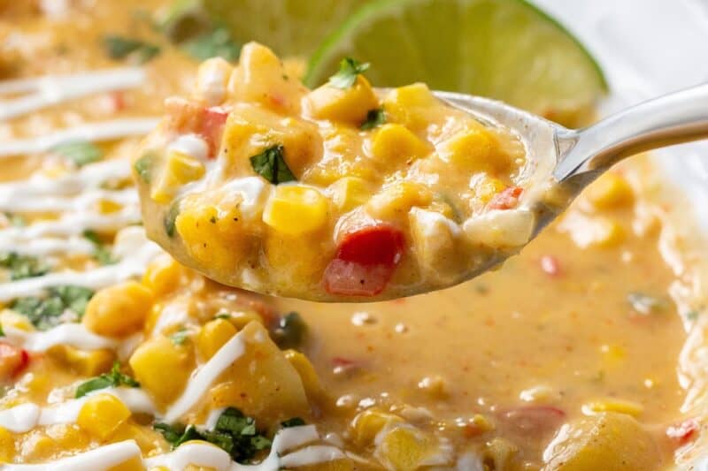 A bowl of corn chowder with a spoonful being dipped out.
