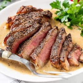 A sliced steak on a platter over brandy cream sauce.