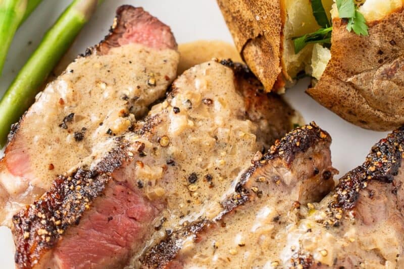 A closeup of a plate with sliced steak drizzled with a cream sauce.