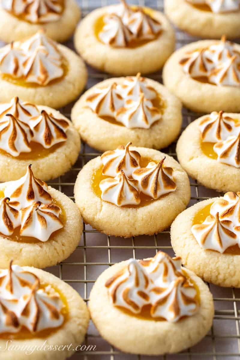 Lemon meringue pie cookies topped with toasted meringue on a cooling rack.