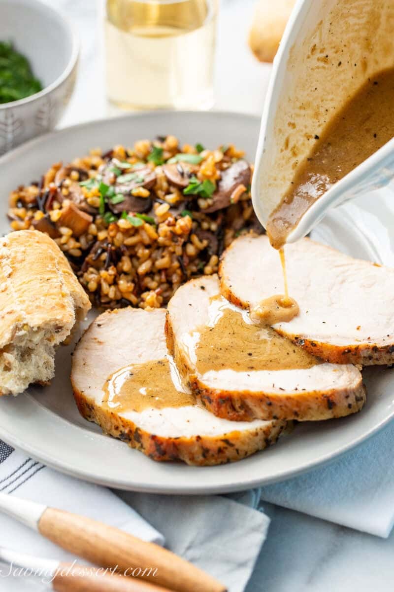 Sauce being poured over three slices of pork roast.